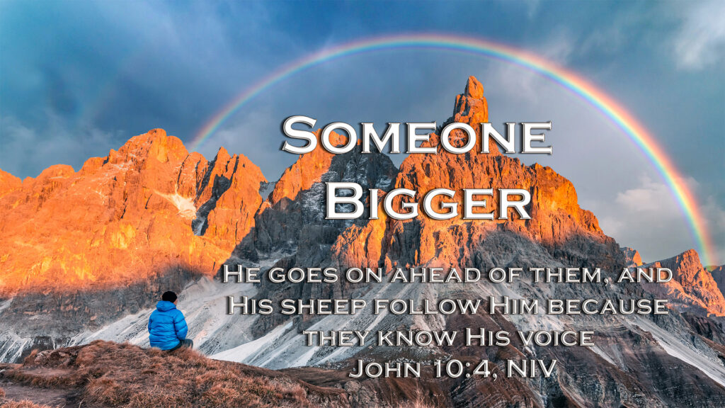 Man sitting looking at Mountain and the rainbow above the mountain